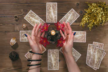 Wall Mural - Tarot cards and hands of fortune teller on wooden table background.