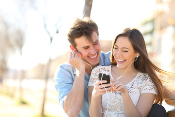 Poster - Joyful couple listening to music from a smartphone in a pak