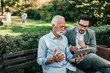 © bnenin - Two handsome business men looking at tablet while sitting on the bench.
