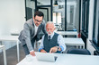 © bnenin - Business people working on laptop. Senior and young business man looking at laptop screen.