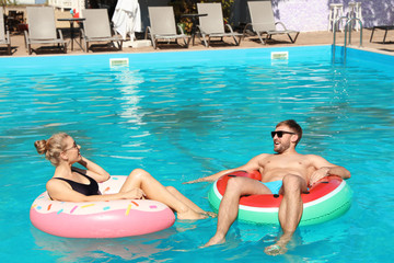 Canvas Print - Happy young couple with inflatable rings in swimming pool