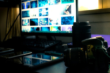 Closeup of black Modern Digital DSLR camera in Photography Workstation studio with Computer and monitor.