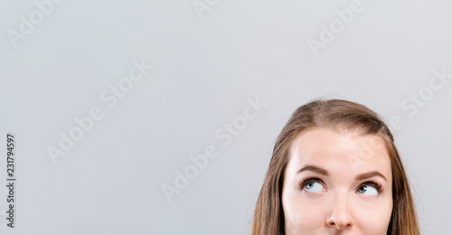 Cuadros en Lienzo Young woman looking upwards on a gray background