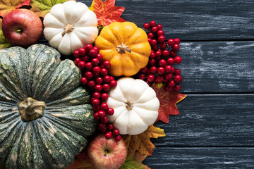 Wall Mural - top view of autumn maple leaves with pumpkin and red berries on old wooden background. thanksgiving 