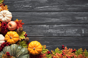 top view of autumn maple leaves with pumpkin and red berries on old wooden background. thanksgiving 