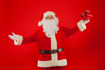 Photo of Santa Claus gloved hand with giftbox, on a red backgrou