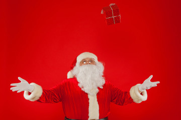 Photo of Santa Claus gloved hand with giftbox, on a red backgrou