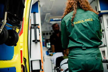 Sticker - Paramedics moving a patient on a stretcher into an ambulance