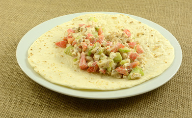 Wall Mural - Chopped chicken, cucumbers, tomatoes with sour cream on tortilla on plate for making chicken wrap 