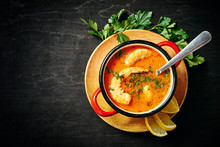 Traditional Thai Soup With Shrimp And Coconut Milk In A Red Pot And A Spoon With Parsley And Lemon