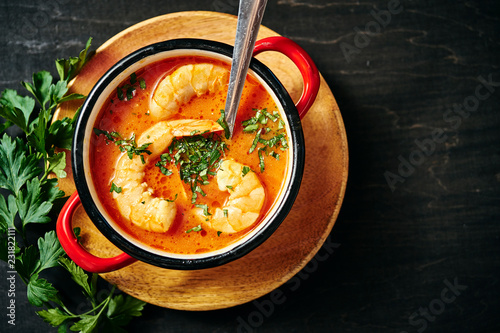 Fotomural traditional Thai soup with shrimp and coconut milk in a red pot and a spoon with