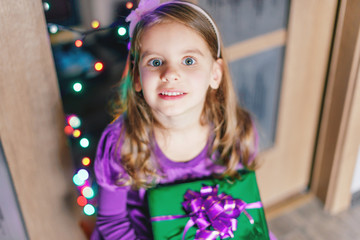 Merry Christmas! Happy child girl with christmas gift at evening home.	