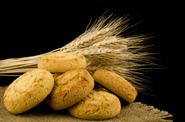 homemade cookies and spikelets of wheat isolated on black background close-up