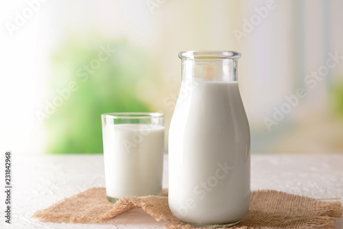 Fotomural Bottle and glass of tasty milk on light table