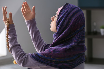 Wall Mural - Young Muslim woman praying at home