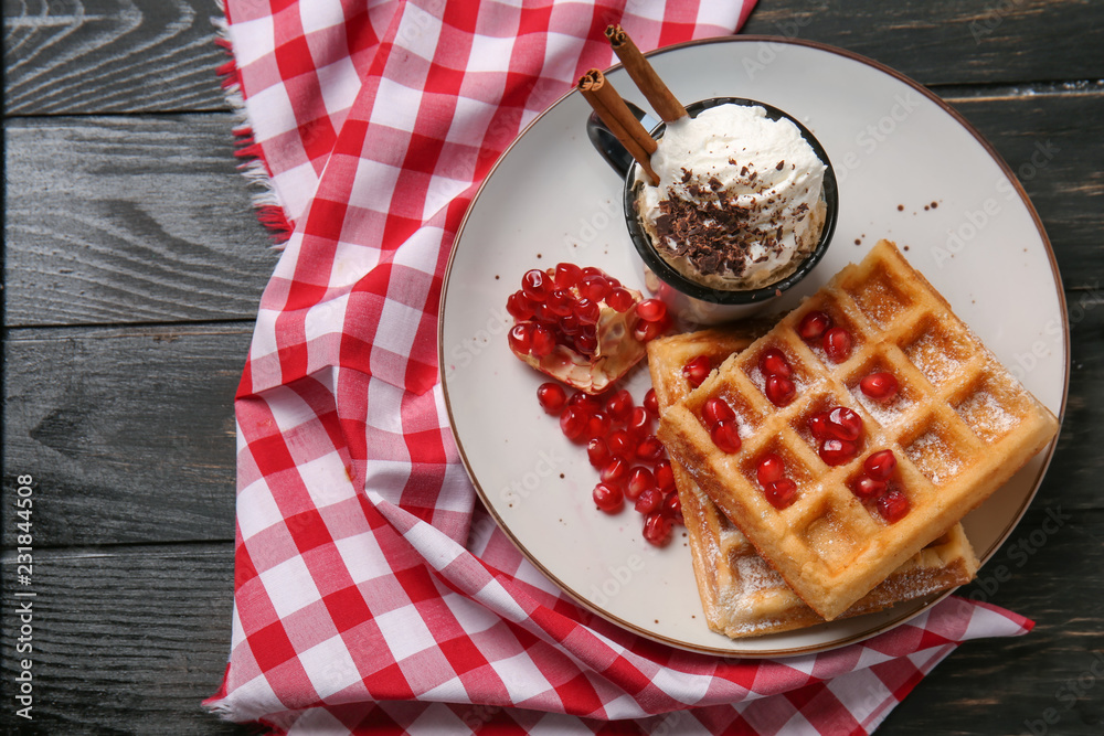 Tasty waffles with pomegranate seeds and ice cream on plate