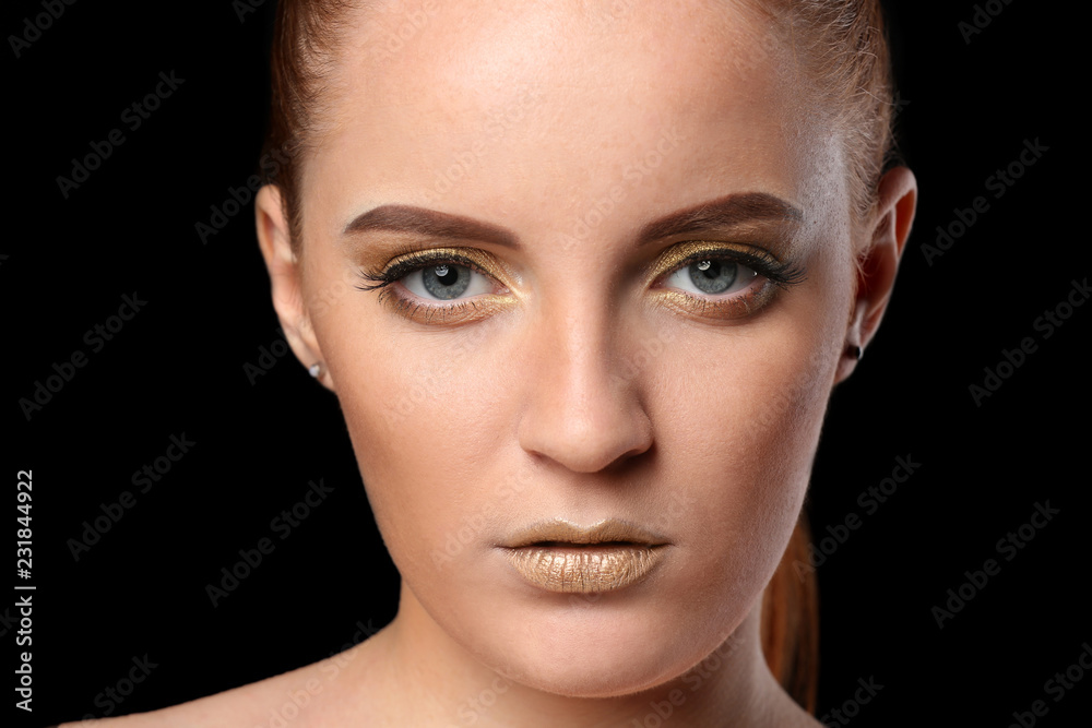 Beautiful woman with golden make up against dark background