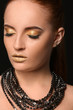 © Pixel-Shot - Beautiful woman with golden make up against dark background