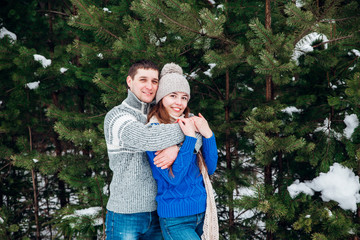 Wall Mural - Young couple hugging and kissing in the forest in winter.