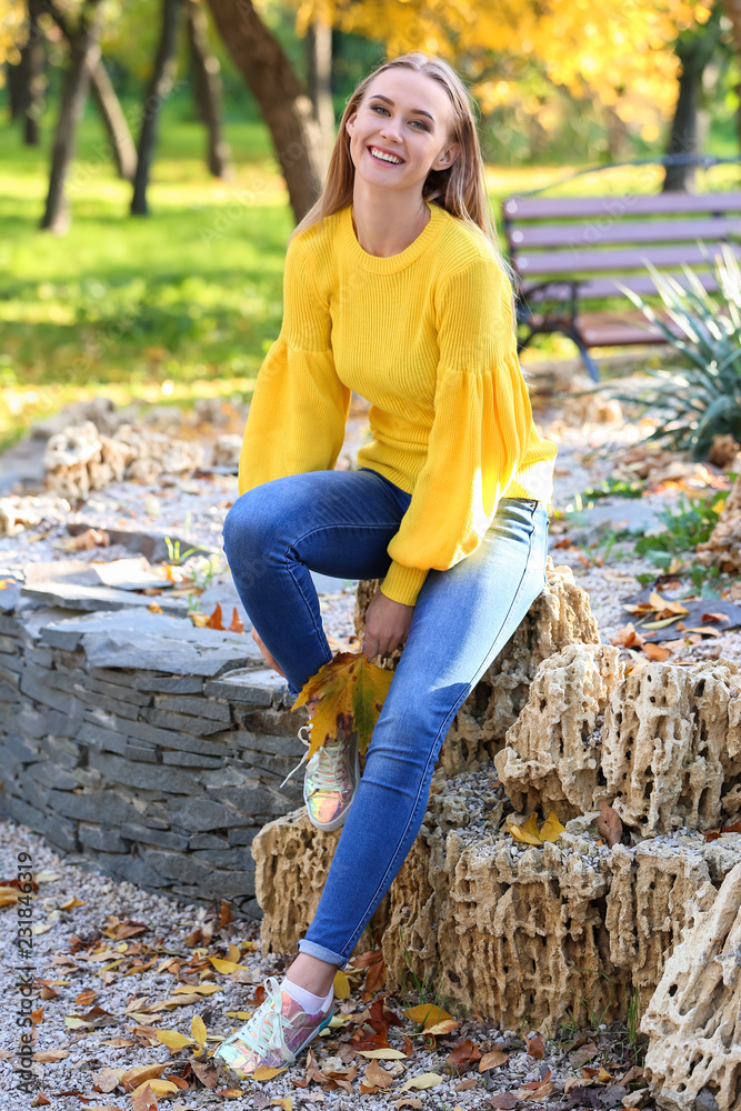 Beautiful young woman with autumn leaf in park