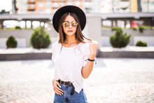 Beautiful Brunette Young Woman Wearing Hat And Sunglasses And Walking On The Street