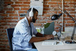 © LUMINA IMAGES - Young African businessman with headphones typing on his laptop at work.