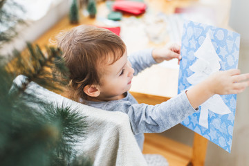 Cute little girl preparing christmas picture with christmas tree.