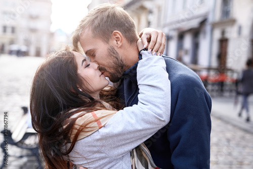 Fotomural Portrait of a young romantic enamoured couple hugging and kissing during the city walk
