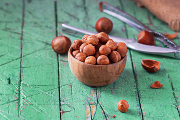 Hazelnuts in wooden bowl on old cyan green table. Copy space.