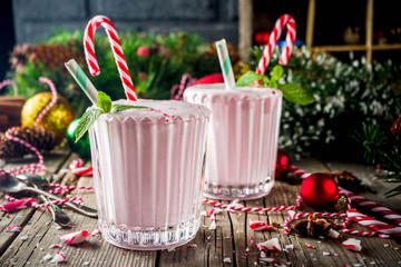 christmas sweet cold drink, homemade peppermint candy cane milkshake in two glasses, old wooden back