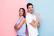 © Drobot Dean - Image of young man and woman in casual wear standing back to back with arms crossed, isolated over colorful background