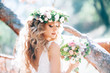 beautiful bride in nature in a coniferous forest in a wreath on her head and a luxurious wedding dress