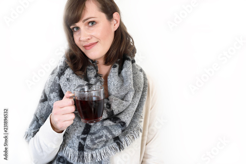 Fotografie, Obraz Glückliche junge Frau trinkt Glühwein Tee oder Punsch und lacht vor weißem Hinte