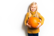 A Cute Girl 5 Year Old Posing In Studio With Pumpkin