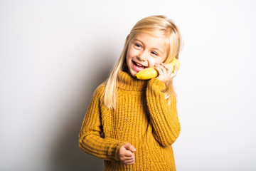 Wall Mural - A Cute girl 5 year old posing in studio with banana fruit