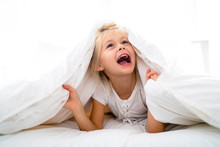 A Cheerful Little Girl In Bed Having Fun