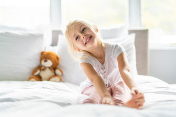 A Cheerful little girl in bed having fun