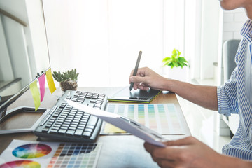 Poster - Image of male creative graphic designer working on color selection and drawing on graphics tablet at workplace with work tools and accessories in workspace