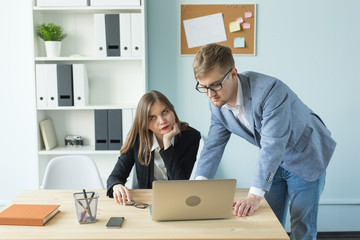 Business, teamwork and people concept - woman and man are working together in office