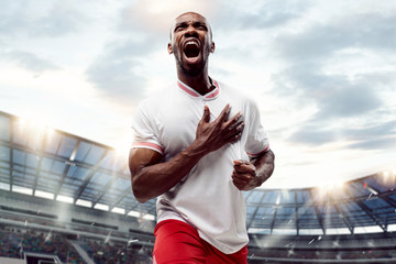 The football african player in motion on the field of stadium at day. The professional football, soccer player and human emotions concept. The win winner , victory concept