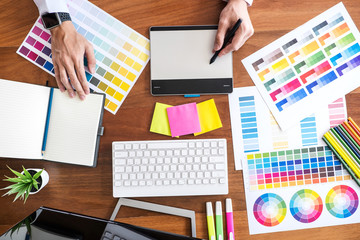 Poster - Image of male creative graphic designer working on color selection and drawing on graphics tablet at workplace with work tools and accessories, top view