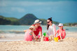 © travnikovstudio - Family of four making sand castle at tropica beach