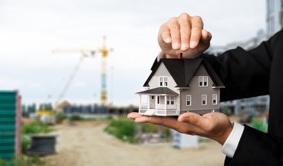 Poster - Male hands holding house model on background