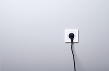 Electric White Socket And One Plugged In Power Cord On White Wall Background