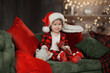 © oes - Christmas cute toddler girl in Santa hat holding a a gift box. Family holiday concept.