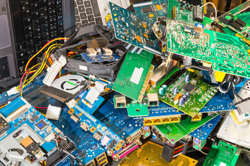 E-waste pile from discarded laptop parts. Connectors, PCB, notebook keyboards. Colorful background from PC components. Idea of electronic waste sorting, recycling and disposal. Full depth of field.