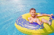 Cheerful smiling boy enjoys floating on inflatable ring in the swimming pool in aqua park