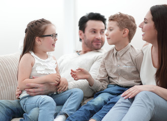 Wall Mural - loving parents with children sitting on the couch