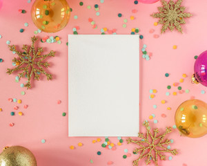 Mock up card on a pink background with their Christmas decorations and confetti. Invitation, card, paper. Place for text