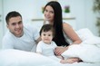 © ASDF - Cheerful family having fun together lying on a bed